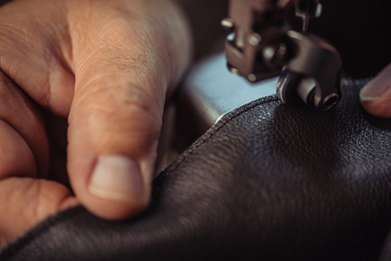 Close-up of a craftsman stitching leather upholstery by hand