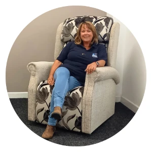 Adele, the Retail Manager of Bush Healthcare Aberdare, smiling while seated comfortably in a patterned rise and recliner armchair.
