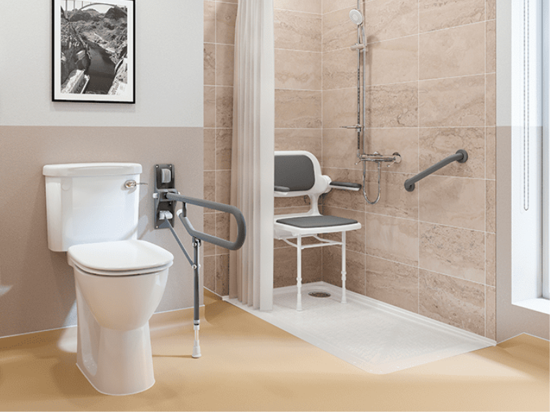A safe and modern accessible walk-in shower with a low-level tray, a built-in shower seat, grab rails, and a toilet with a support handle.