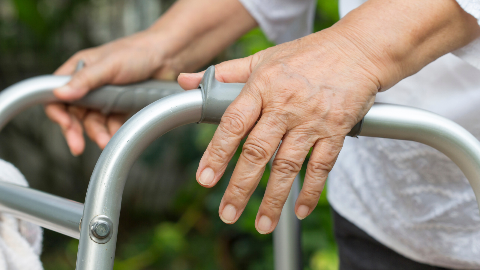 Close-up of hands holding the handles of a rollator