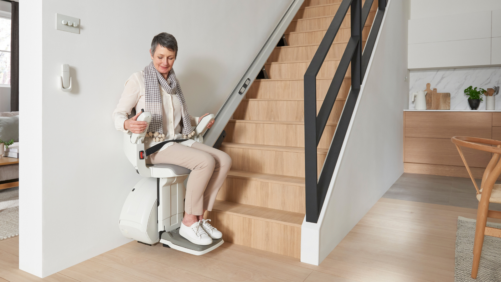 Man riding a straight stairlift in a modern hallway