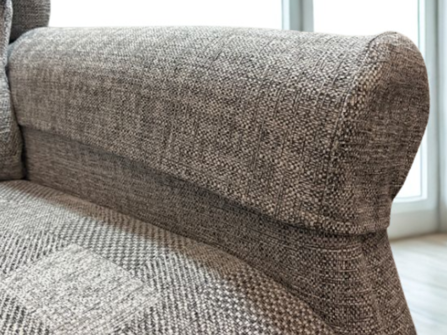 Close-up of a brown, patterned arm cover accessory secured over the armrest of a riser recliner chair, emphasising protection and style.