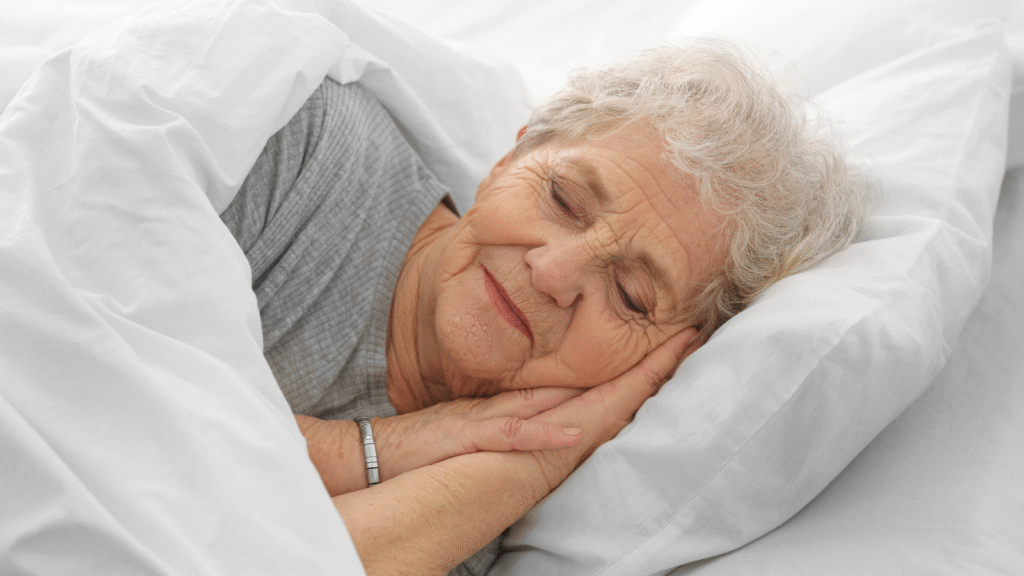 Close-up of an elderly woman sleeping peacefully and comfortably on a white pillow, representing the restful sleep provided by an adjustable care bed.
