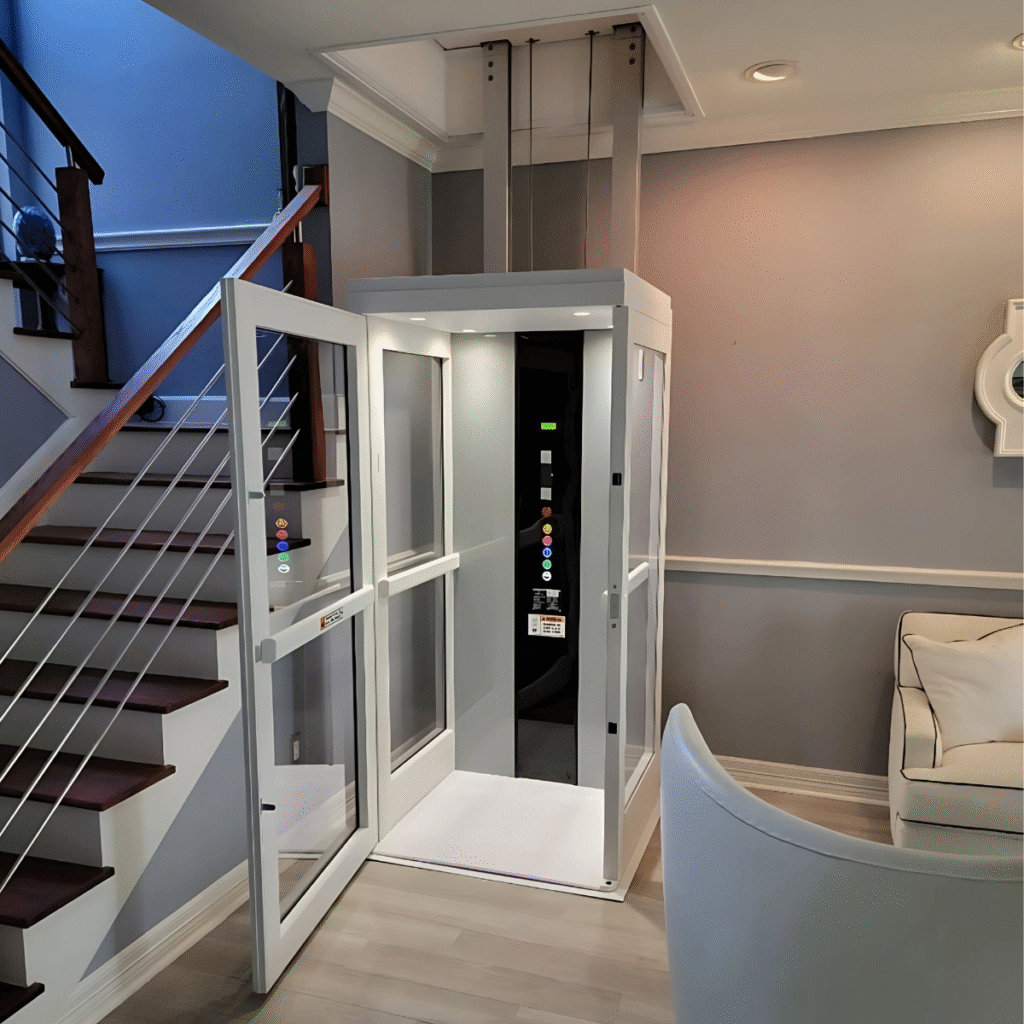 White and glass Pollock indoor vertical lift with its glass door open, installed in a contemporary home foyer with a dark wood staircase and light wood flooring.