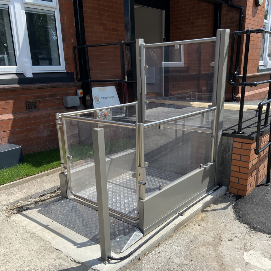 Silver Pollock Steplift Outdoor vertical platform lift installed adjacent to a short set of brick steps, demonstrating a 1 metre rise for home access.