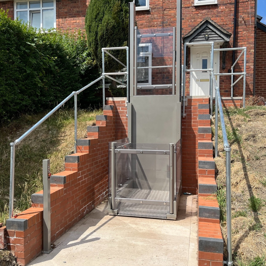 White and glass Pollock indoor vertical lift installed in a bright residential hallway, showcasing its capability for a 3 metre rise for seamless floor access.