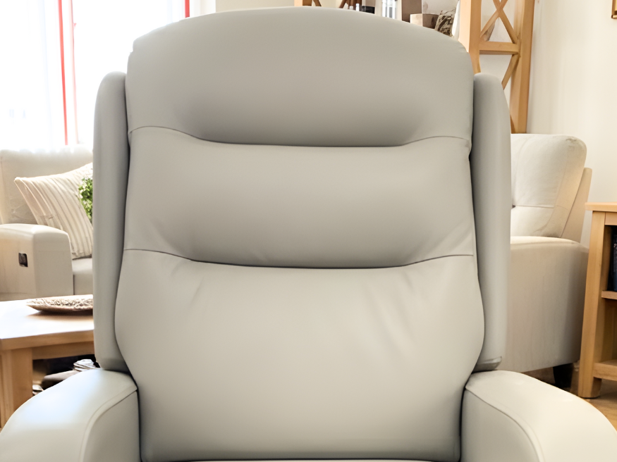 Close-up of a light grey or beige Supremo faux leather fabric, showing the smooth texture and light padding of the upholstery option for riser recliner chairs.