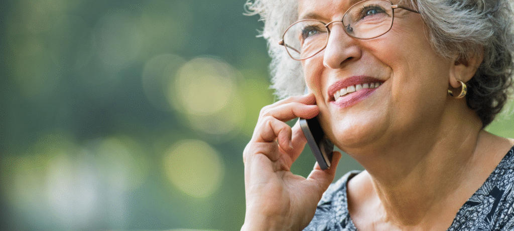 Smiling elderly woman talking on a mobile phone, representing easy access to Bush Healthcare customer service and expert advice.