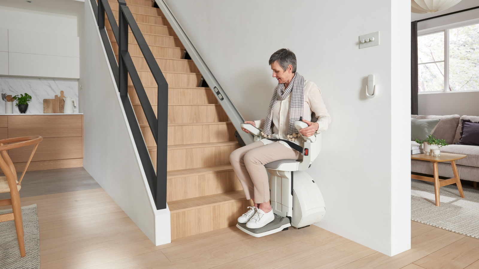 Man riding a straight stairlift beside an open living area