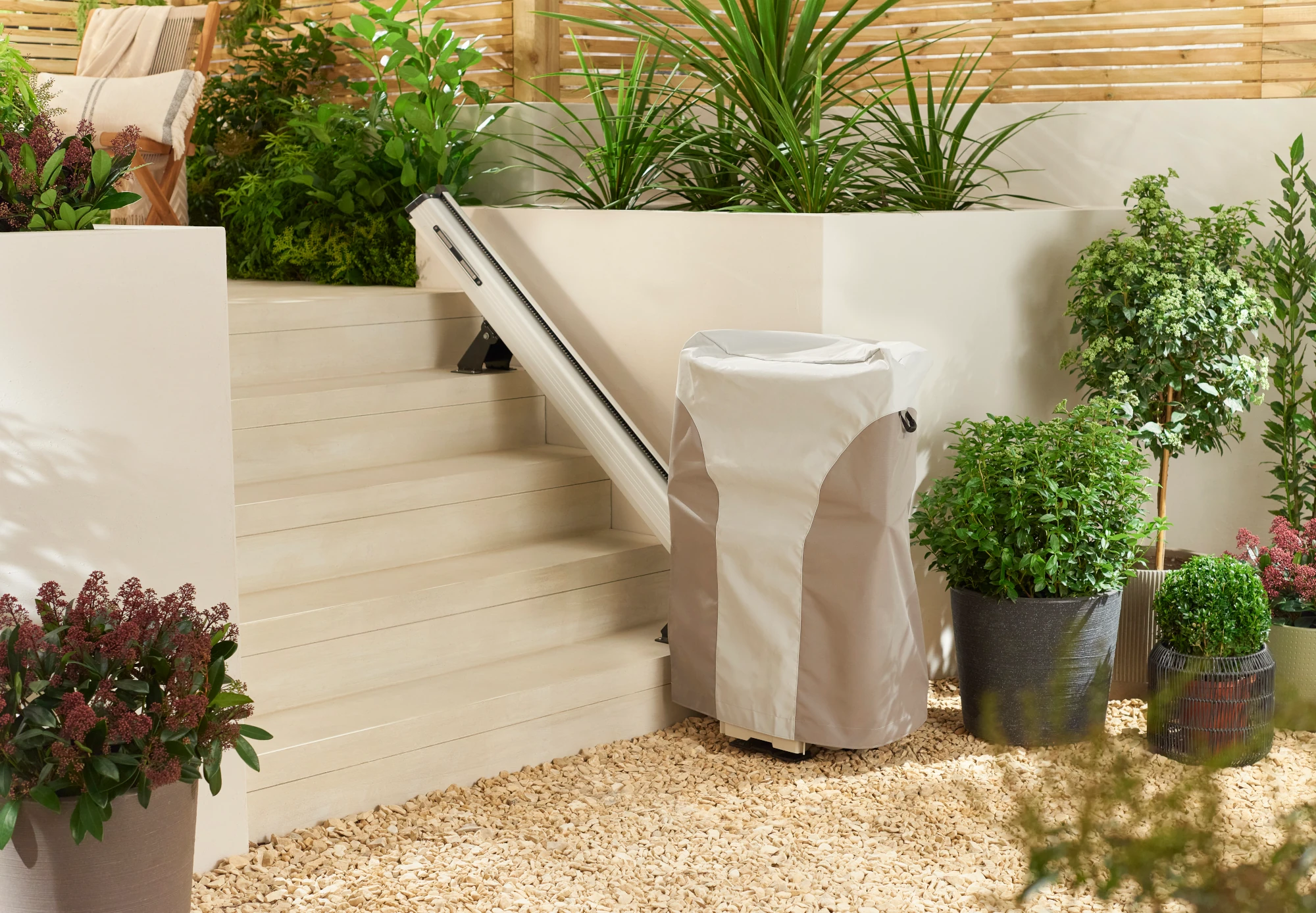 Outdoor stairlift under its weather cover beside garden steps