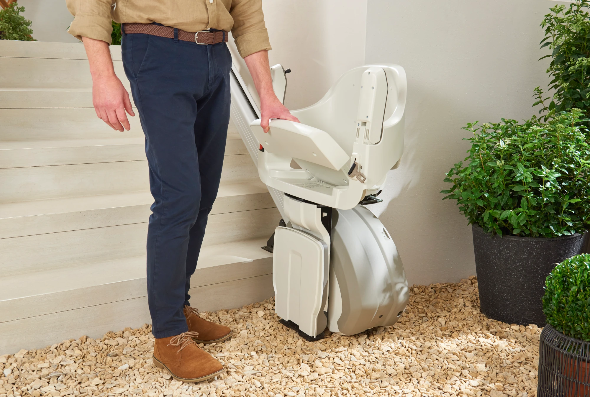 Man folding the seat of an outdoor stairlift at the top of garden steps